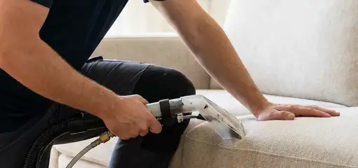 Professional upholstery cleaner deep-cleaning a fabric sofa with a handheld extraction tool, Salt Lake City, UT.